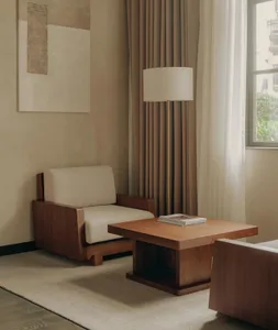 Modern interior living room featuring a wooden coffee table, beige upholstered armchair, floor lamp, and neutral color palett