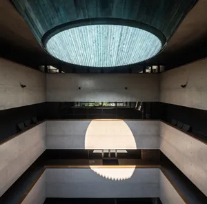 An interior office space featuring modern concrete architecture with large circular light fixtures.