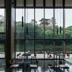 Modern restaurant interior with large glass windows and a concrete floor.