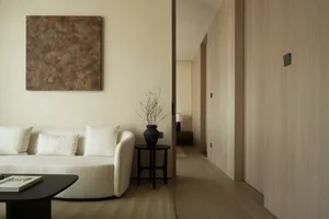 A modern minimalist living room with neutral-toned fabrics, featuring a minimalistic sofa and a sleek coffee table.