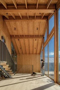 A modern residential interior with wooden walls, a staircase, and large windows.