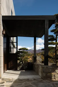 A stone veranda with a view of the mountains and autumn trees.