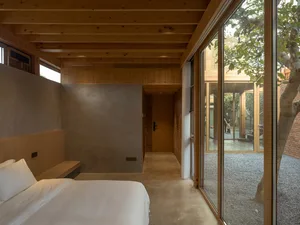 Modern minimalist bedroom with a concrete floor and wooden elements.