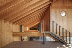 Modern loft apartment featuring wooden structural elements and a metal staircase.