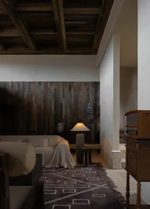 A modern minimalist living room with white furniture, wooden ceiling beams, and a marble floor, featuring a floor lamp and a
