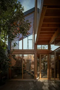 Modern residential interior with glass walls, wooden beams, and concrete floors.