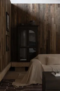 A cozy living room with wood-paneled walls and a beige sofa.