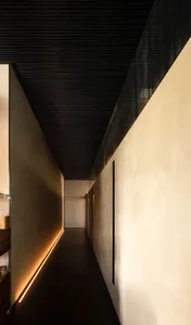 A corridor features a concrete wall illuminated by LED lighting along the floor.