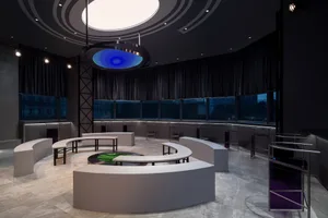 A modern minimalist conference room with white seating, circular lighting, and large windows.