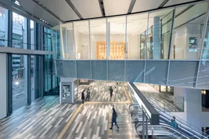Modern shopping center interior with glass walls, concrete floors, and tiled accents.