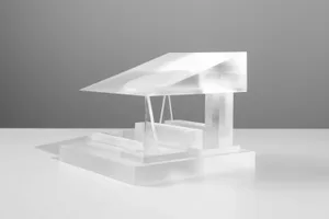 A transparent plastic model of a house on a white surface.