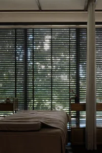 A minimalist bedroom with window blinds and a curtain.