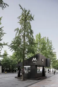 Black metal food vendor stand with an 'M' logo and a modern exterior design in an open urban area.