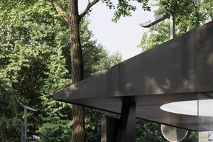 modern design building with metal roof and trees in background