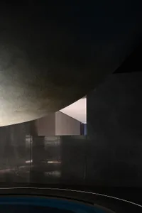 Modern house entrance featuring metal-clad walls illuminated by light from above.