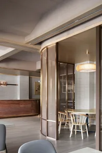 Interior of a modern coffee shop with metal and glass partitions, wooden furniture, and a contemporary design.
