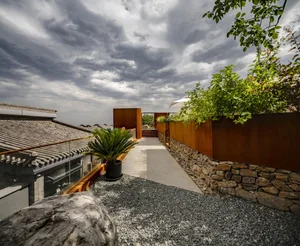 A modern rooftop garden with stone walls and a steel fence.