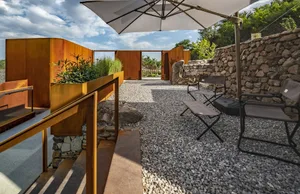 Outdoor patio area with concrete pavement, rocks, and seating area.
