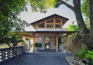 Minimalist cafe exterior with wooden framing, concrete columns, and terrazzo floor.