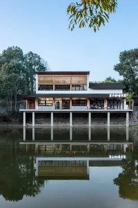 Modern restaurant building with wooden accents and concrete columns surrounded by calm water