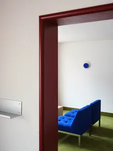 A modern room with a blue sofa and green flooring.