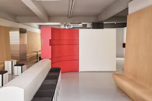 Modern minimalist office with sleek wooden benches, glass dividers, and metal supports.