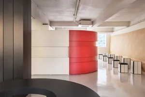 現代辦公空間，混凝土牆面搭配紅色圓柱結構。