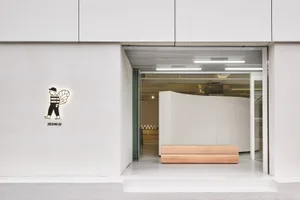 A minimalist office space featuring a white concrete and wood design