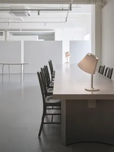 Minimalist office space featuring wooden furniture and a long table.