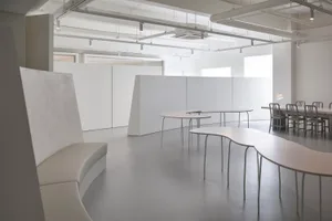 A minimalist office space featuring white surfaces and glass elements.