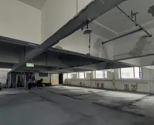 Minimalist office space with concrete walls and a high ceiling.