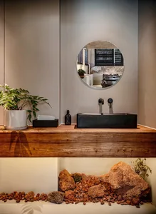 An industrial-style bathroom with a wooden vanity, black sink, and rock decor.