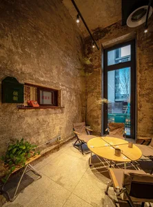 Industrial-style co-working space with concrete walls, wooden table and chairs, and a large window overlooking an urban lands