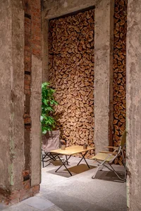 Industrial-style interior design featuring stacked firewood and seating area.