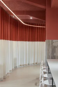 A modern cafe interior featuring textured red curtains.