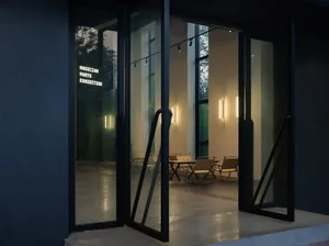 An exhibit space accessible through glass doors with ambient lighting and a view of outdoor seating.