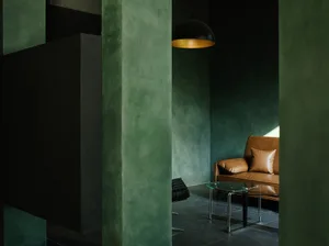 A modern, industrial-style living room with a concrete floor, minimalist furniture, and a cozy seating area.