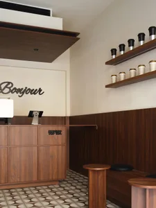 A modern cafe interior featuring wooden furniture and shelves.