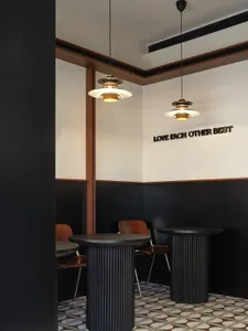 Modern cafe interior with white and black color scheme and wooden pendant lights hanging from the ceiling.