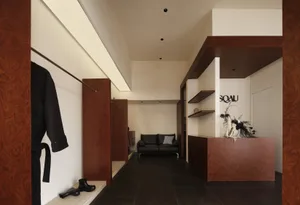 A modern clothing store with wooden paneling, featuring a minimalist design with sleek black furniture and a wooden reception