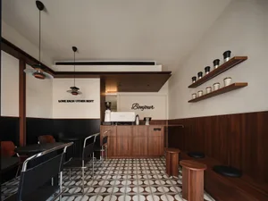 A modern coffee shop interior featuring wooden and metal elements and ceramic tiles on the floor.