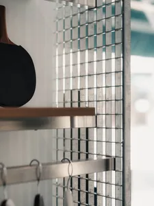 A minimalist interior design featuring a metal grid wall and wood accents.