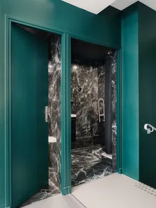A modern bathroom with marble tiles and green walls and door frames.