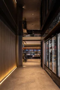 A modern restaurant corridor with concrete flooring, warm ambient lighting, and glass display cases.