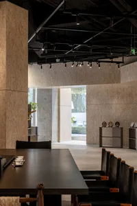 An industrial-style restaurant interior with concrete walls, minimalist decor, and modern seating.