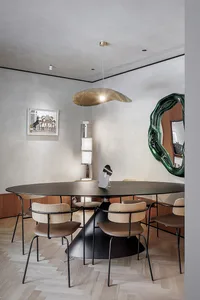 Modern dining room with a metal and wooden table, chairs, and pendant light.