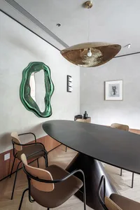Modern interior design featuring a metallic dining table with wooden chairs and a contemporary art piece.