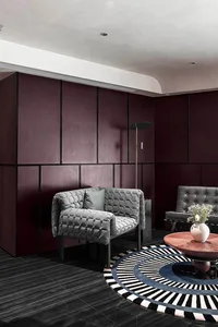 A modern living room with wooden walls and furniture, featuring a round rug and minimalist design.