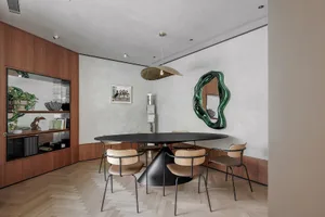 A modern dining room with a black oval table, wooden chairs, and metallic accents. Features include minimalist design and con