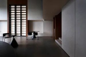 Modern, minimalist interior with concrete walls and floor, featuring a sleek, black dining table and chairs.